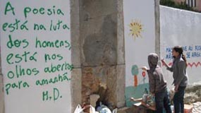 Foto crianças a pintar mais um bocado do muro, versos de Mário Dionísio